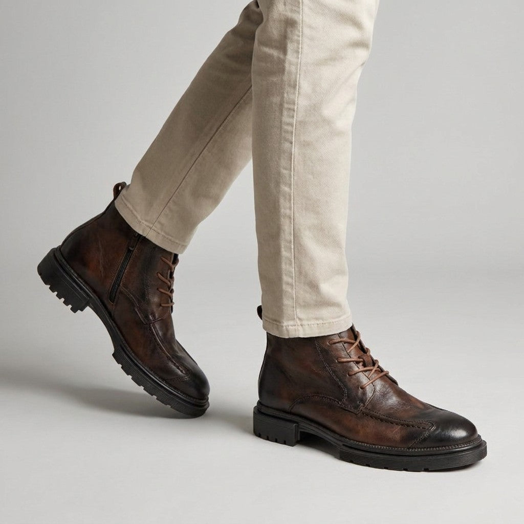 Brown Nils boots worn with stone chinos, walking side view showing the apron seam