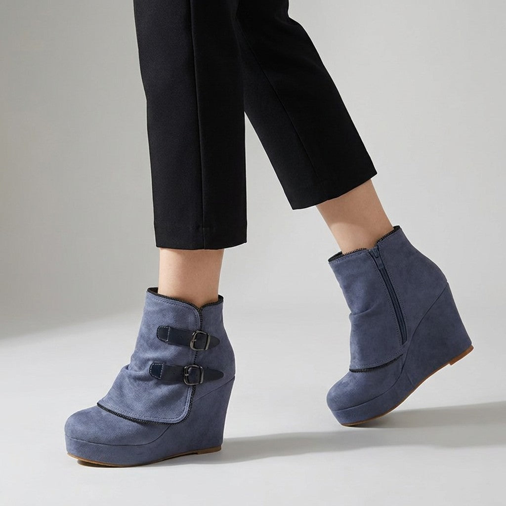 Blue Saskia wedge ankle boots worn mid-stride, outer buckles and inner side zip visible
