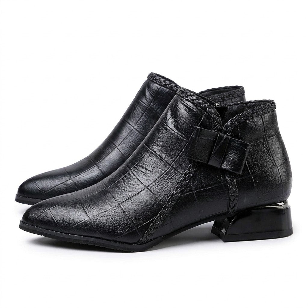 Pair of black Tamsin pointed ankle boots on white, outer side with leather bow and braided trim
