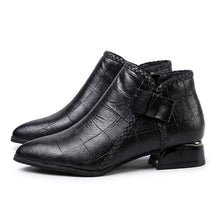 Pair of black Tamsin pointed ankle boots on white, outer side with leather bow and braided trim