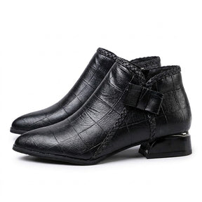 Pair of black Tamsin pointed ankle boots on white, outer side with leather bow and braided trim