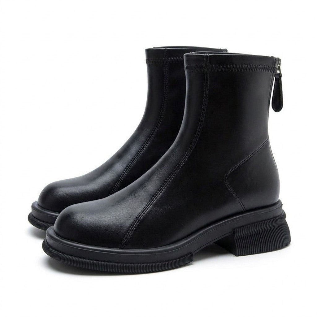 Pair of black Liesel leather ankle boots on white, side view with chunky ridged sole