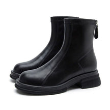 Pair of black Liesel leather ankle boots on white, side view with chunky ridged sole