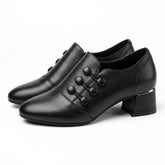 Pair of black Clemence leather shoe boots with corded buttons, side view on white
