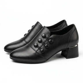 Pair of black Clemence leather shoe boots with corded buttons, side view on white