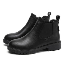 Pair of black Ines leather Chelsea boots on white, side view with chunky cleated sole