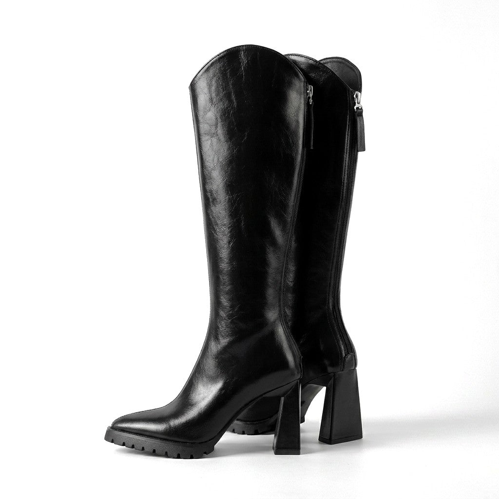 Pair of black Mirela leather knee high boots with flared block heels and lug soles on white