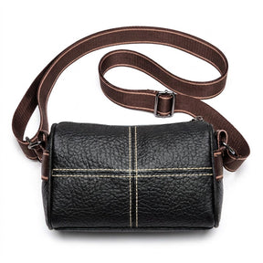 Front view of the Bellamy black pebbled leather barrel crossbody bag with cream cross stitching and wide woven strap