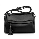 Front view of the Odalys black pebbled leather barrel crossbody bag with tassel on a white background