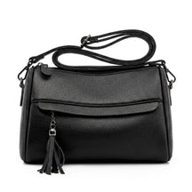 Front view of the Odalys black pebbled leather barrel crossbody bag with tassel on a white background