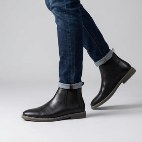 Falk black Chelsea boots worn with turned-up jeans, walking side view