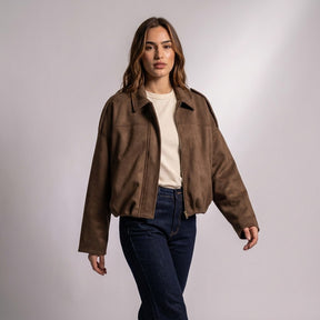 Model walking in the Brown Brisa suede bomber worn open over a cream T-shirt and dark jeans