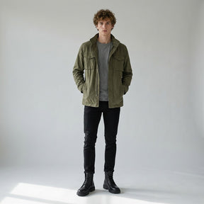 Model in an olive field jacket and black jeans wearing Matthis black work boots