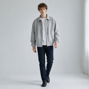 Model walking in the grey Emeric suede jacket worn open over a white T-shirt with dark jeans