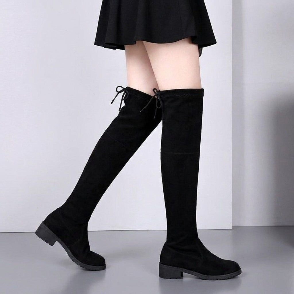 Oriane black stretch suede boots worn mid-stride, shaft rising above the knee
