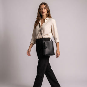 Model walking with the black Solveig crossbody bag on its long cord strap