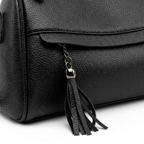 Close-up of the fringed black leather tassel and gunmetal cap on the Odalys front zip pocket