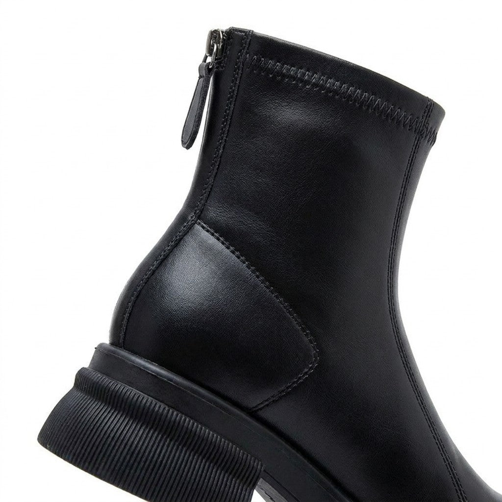 Close-up of the Liesel back zip pull tab, zigzag-stitched top band and ribbed block heel