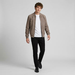 Model walking in the taupe Corvin suede bomber worn open with black trousers